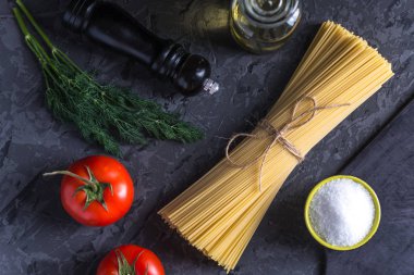 Pişmemiş İtalyan makarna spagetti domates sosu karanlık bir arka plan üzerinde için malzemeler. Gıda tasarım kompozisyon kavramı.