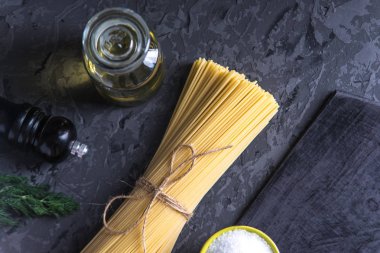 Pişmemiş İtalyan makarna spagetti domates sosu karanlık bir arka plan üzerinde için malzemeler. Gıda tasarım kompozisyon kavramı.