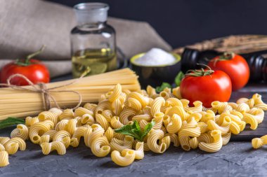 Pişmemiş makarna çeşitleri fırıncı ve spagetti için karanlık bir arka plan üzerine domates sosu malzemeler ile. Gıda tasarım kompozisyon kavramı.