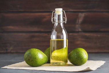 Yeşil avokado meyve ve cam şişe koyu arka plan üzerine yağda. Kavram organik Eko ürünler gıda ve kozmetik prosedürler için