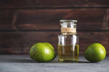 Yeşil avokado meyve ve cam şişe koyu arka plan üzerine yağda. Kavram organik Eko ürünler gıda ve kozmetik prosedürler için