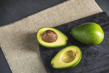 Avokado meyve keten kumaş arka plan üzerinde ikiye böldüm. Kavram organik Eko ürünler gıda ve kozmetik prosedürler için