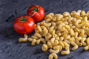 Pişmemiş makarna çeşitleri fırıncı ile karanlık bir arka plan üzerine domates sosu için malzemeler. Gıda tasarım kompozisyon kavramı.