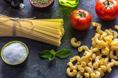 Pişmemiş makarna çeşitleri fırıncı ve spagetti için karanlık bir arka plan üzerine domates sosu malzemeler ile. Gıda tasarım kompozisyon kavramı.