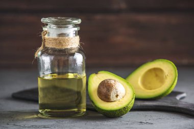 Yeşil avokado meyve ve cam şişe koyu arka plan üzerine yağda. Kavram organik Eko ürünler gıda ve kozmetik prosedürler için