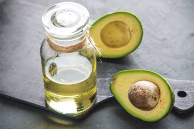 Yeşil avokado meyve ve cam şişe koyu arka plan üzerine yağda. Kavram organik Eko ürünler gıda ve kozmetik prosedürler için