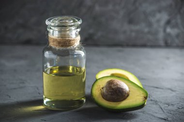 Yeşil avokado meyve ve cam şişe koyu arka plan üzerine yağda. Kavram organik Eko ürünler gıda ve kozmetik prosedürler için
