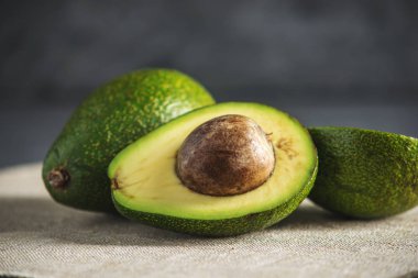 Avokado meyve keten kumaş arka plan üzerinde ikiye böldüm. Kavram organik Eko ürünler gıda ve kozmetik prosedürler için