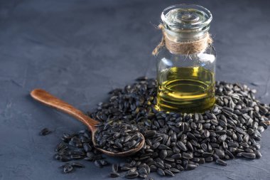 Ayçiçeği tohumu kaşık ve bir cam şişe masanın üzerinde altın yağ ile bir yığın. Bitkisel yağlar ile sağlıklı beslenme kavramı.