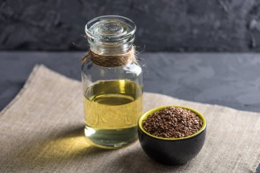 Bir yığın ve keten tohumu Keten tohumu altın cam şişe masanın üzerinde karanlık bir arka plan üzerinde yağda. Omega 3 yağ asitleri ile kavram sağlıklı beslenme.