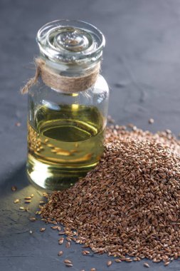 Bir yığın ve keten tohumu Keten tohumu altın cam şişe masanın üzerinde karanlık bir arka plan üzerinde yağda. Omega 3 yağ asitleri ile kavram sağlıklı beslenme.