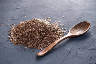 Keten tohumu bir yığın karanlık bir arka plan üzerine kaşıkla. Omega 3 yağ asitleri ile sağlıklı beslenme kavramı.