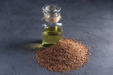 Bir yığın ve keten tohumu Keten tohumu altın cam şişe masanın üzerinde karanlık bir arka plan üzerinde yağda. Omega 3 yağ asitleri ile kavram sağlıklı beslenme.