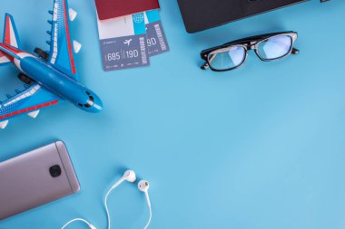 Uçak, uçak bileti, pasaport, gözlük ve telefon ile mavi bir arka plan üzerinde kulaklık. Üstten görünüm. Planlama ve seyahat için hazırlanıyor kavramı