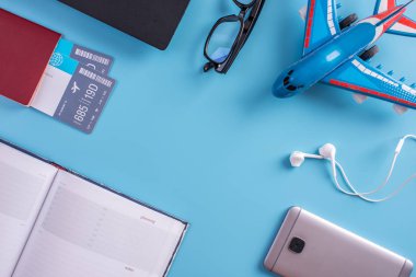 Uçak, uçak bileti, pasaport, dizüstü bilgisayar ve telefon ile mavi bir arka plan üzerinde kulaklık. Üstten görünüm. Planlama ve seyahat için hazırlanıyor kavramı