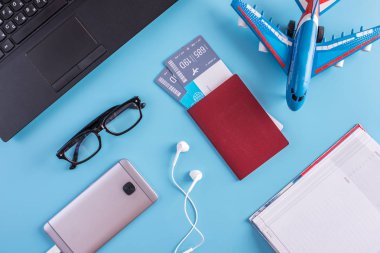 Uçak, uçak bileti, pasaport, dizüstü bilgisayar ve telefon ile mavi bir arka plan üzerinde kulaklık. Üstten görünüm. Planlama ve seyahat için hazırlanıyor kavramı