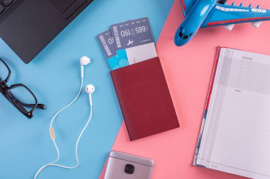 Uçak, uçak bileti, pasaport, dizüstü bilgisayar ve telefon kulaklık üzerinde pastel arka plan ile. Üstten görünüm. Planlama ve seyahat için hazırlanıyor kavramı