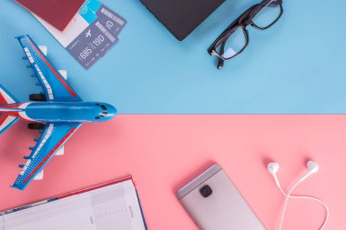Uçak, uçak bileti, pasaport, dizüstü bilgisayar ve telefon kulaklık üzerinde pastel arka plan ile. Üstten görünüm. Planlama ve seyahat için hazırlanıyor kavramı