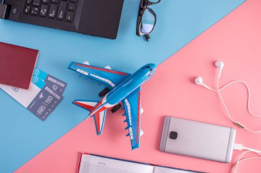 Uçak, uçak bileti, pasaport, dizüstü bilgisayar ve telefon kulaklık üzerinde pastel arka plan ile. Üstten görünüm. Planlama ve seyahat için hazırlanıyor kavramı