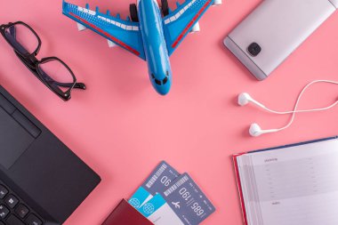 Uçak, uçak bileti, pasaport, dizüstü bilgisayar ve telefon kulaklık üzerinde pembe bir arka plan ile. Üstten görünüm. Planlama ve seyahat için hazırlanıyor kavramı