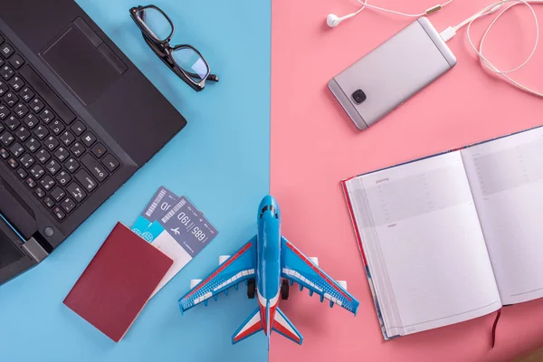 Plane, air tickets, passport, notebook and phone with headphones on pastel background. The view from the top. The concept of planning and preparing for the travel