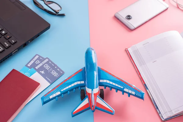 Plane, air tickets, passport, notebook and phone with headphones on pastel background. The view from the top. The concept of planning and preparing for the travel