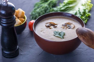 Kremalı mantar çorbası masanın üzerinde kahverengi bir tabak içinde. Koyu arka plan. Sağlıklı sonbahar vejetaryen geleneksel yemek