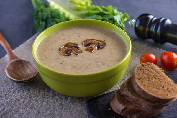 Kremalı mantar çorbası masanın üzerinde yeşil bir kasede. Koyu arka plan. Sağlıklı sonbahar vejetaryen geleneksel yemek