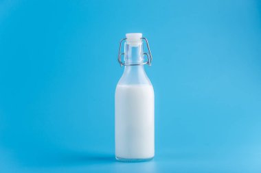 Mavi zemin üzerine taze süt ile cam şişe. Renkli minimalizm. Kalsiyum sağlıklı süt ürünleri kavramı