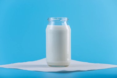 Mavi zemin üzerine taze süt ile cam şişe. Renkli minimalizm. Kalsiyum sağlıklı süt ürünleri kavramı