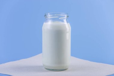 Mavi zemin üzerine taze süt ile cam şişe. Renkli minimalizm. Kalsiyum sağlıklı süt ürünleri kavramı