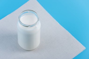 Mavi zemin üzerine taze süt ile cam şişe. Renkli minimalizm. Kalsiyum sağlıklı süt ürünleri kavramı