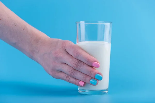 Mano Una Mujer Sostiene Vaso Leche Fresca Sobre Fondo Azul — Foto de Stock