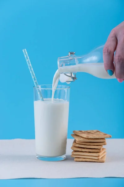 여자의 유리와 파란색 배경에 쿠키에 병에서 신선한 우유를 따른다 다채로운 — 스톡 사진