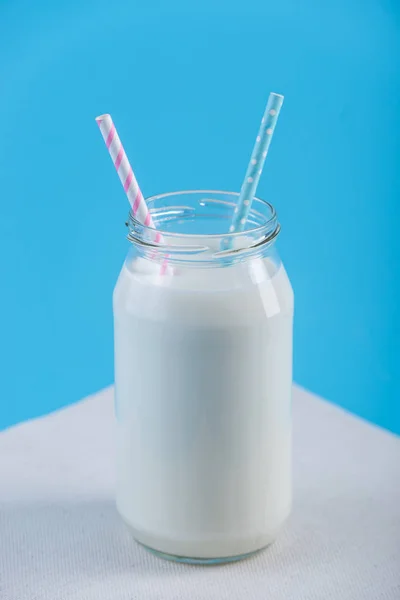 Glasflasche Mit Frischer Milch Mit Zwei Strohhalmen Auf Blauem Hintergrund — Stockfoto