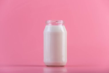 Pembe bir arka plan üzerinde taze süt ile cam şişe. Renkli minimalizm. Kalsiyum sağlıklı süt ürünleri kavramı