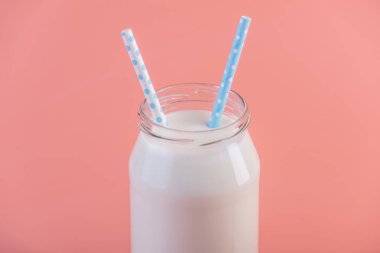 Cam şişe pembe bir arka plan üzerinde iki payet ile taze süt. Renkli minimalizm. Kalsiyum sağlıklı süt ürünleri kavramı