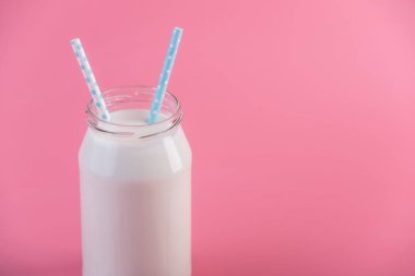 Cam şişe pembe bir arka plan üzerinde iki payet ile taze süt. Renkli minimalizm. Kalsiyum sağlıklı süt ürünleri kavramı