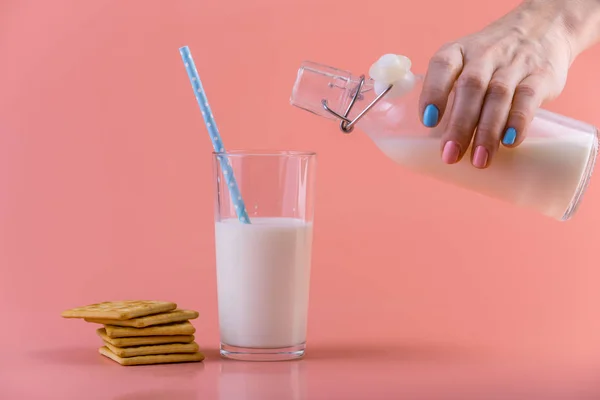 여자의 유리와 분홍색 배경에 쿠키에 병에서 신선한 우유를 따른다 다채로운 — 스톡 사진