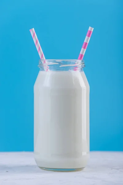 Glasflasche Mit Frischer Milch Mit Zwei Strohhalmen Auf Blauem Hintergrund — Stockfoto