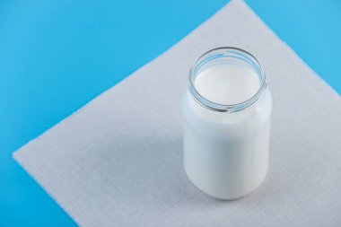 Mavi zemin üzerine taze süt ile cam şişe. Renkli minimalizm. Kalsiyum sağlıklı süt ürünleri kavramı