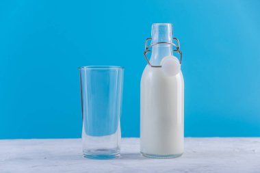 Taze süt ve mavi arka plan cam cam şişe. Renkli minimalizm. Kalsiyum sağlıklı süt ürünleri kavramı