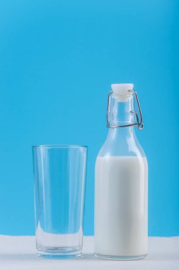 Taze süt ve mavi arka plan cam cam şişe. Renkli minimalizm. Kalsiyum sağlıklı süt ürünleri kavramı