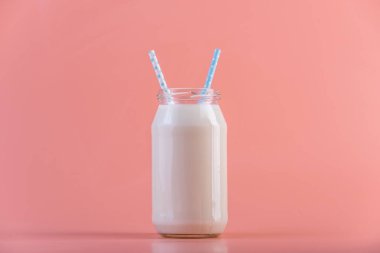 Cam şişe pembe bir arka plan üzerinde iki payet ile taze süt. Renkli minimalizm. Kalsiyum sağlıklı süt ürünleri kavramı