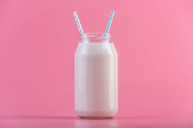 Cam şişe pembe bir arka plan üzerinde iki payet ile taze süt. Renkli minimalizm. Kalsiyum sağlıklı süt ürünleri kavramı