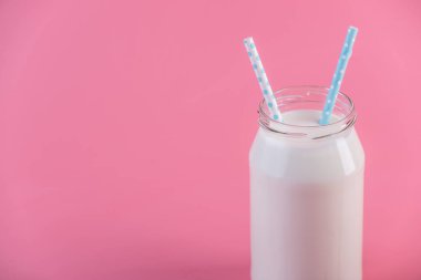 Cam şişe pembe bir arka plan üzerinde iki payet ile taze süt. Renkli minimalizm. Kalsiyum sağlıklı süt ürünleri kavramı