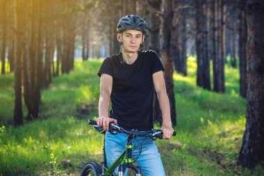 Ormanda ağaçların arasında bir yeşil dağ bisikleti binme bir kask bisikletçi adam. Etkin ve sağlıklı yaşam kavramı