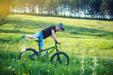 Ormanda ağaçların arasında bir yeşil dağ bisikleti binme bir kask içinde bir adam. Bisikletçi hareket. Etkin ve sağlıklı yaşam kavramı