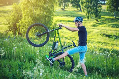 Ormanda ağaçların arasında bir yeşil dağ bisikleti binme bir kask içinde bir adam. Bisikletçi hareket. Etkin ve sağlıklı yaşam kavramı