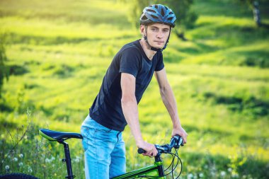 Ormanda ağaçların arasında bir yeşil dağ bisikleti binme bir kask içinde bir adam. Bisikletçi hareket. Etkin ve sağlıklı yaşam kavramı